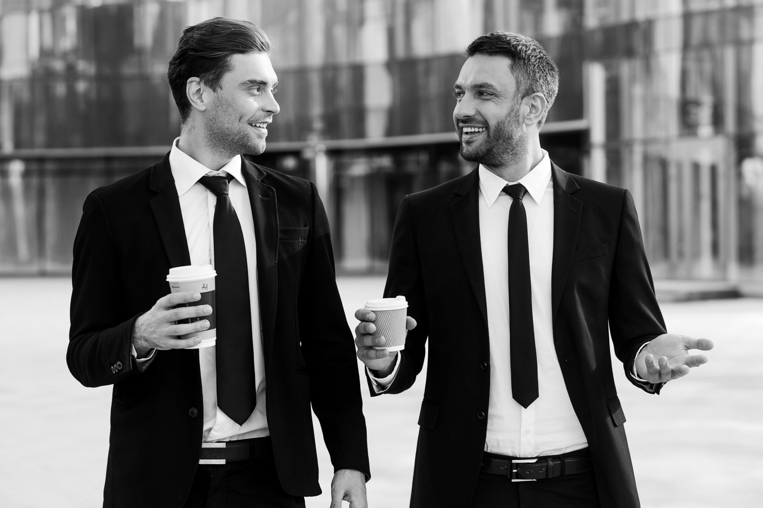 colleagues-friends-two-cheerful-businessmen-holding-cups-coffee-talking-each-other
